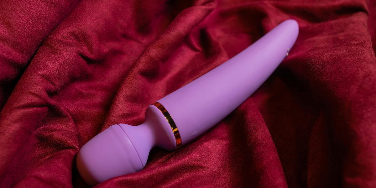 Kobieta w sypialni trzymająca różowy wibrator